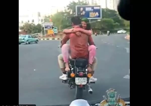 Rides bike with girlfriend sitting on her lap, keeps smiling by hugging boyfriend